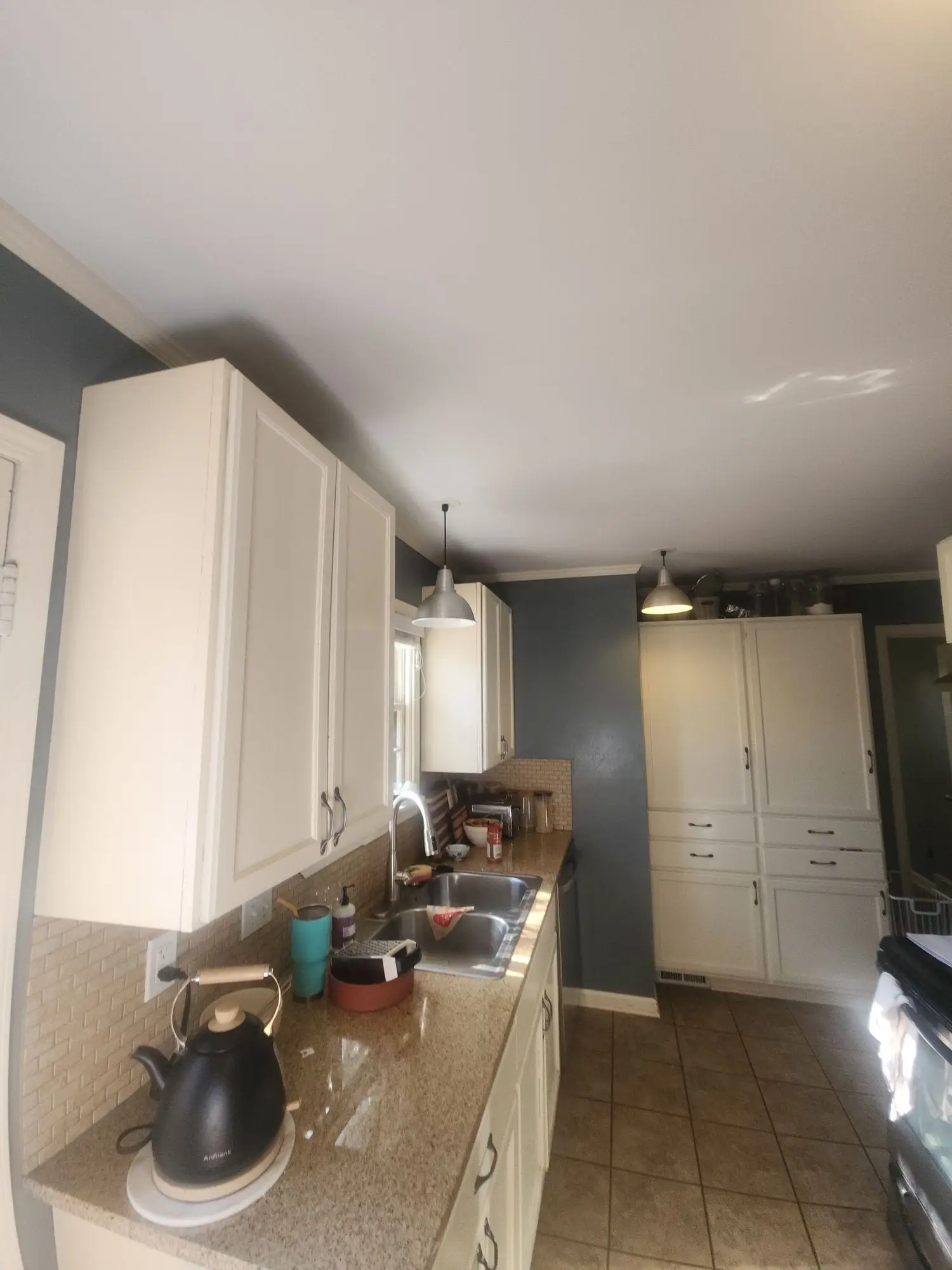 Kitchen with the walls and ceiling repainted, existing white cabinets and tiled floor