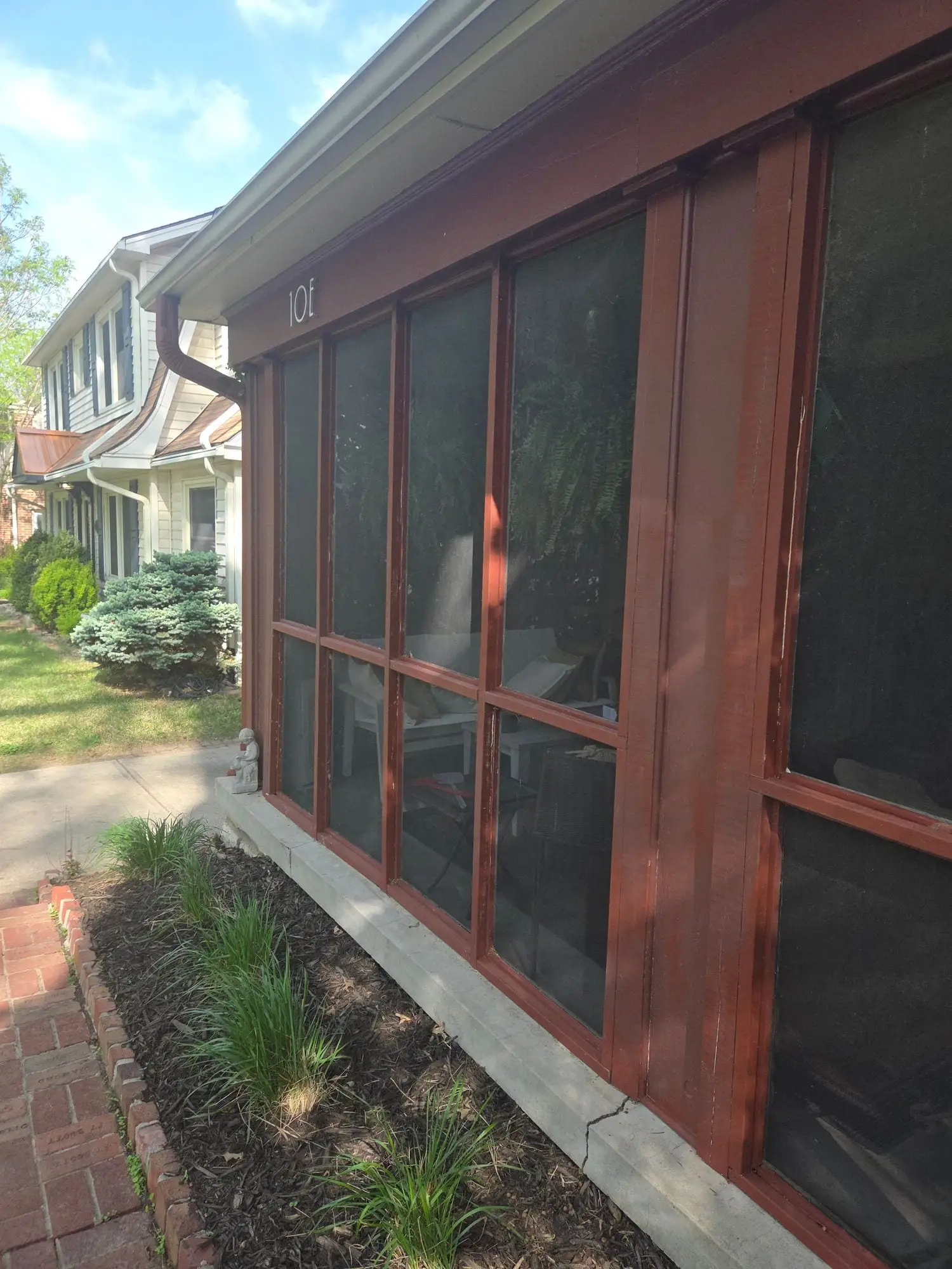 Screened porch with newly painted red-brown window frames, seen from the garden
